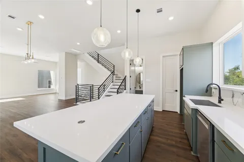 a large kitchen with kitchen island a sink stainless steel appliances and a chandelier