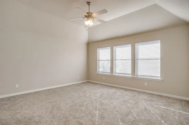 an empty room with chandelier fan and windows