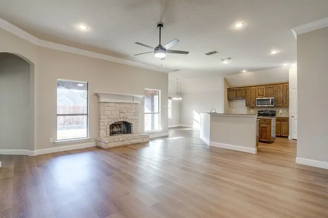 an empty room with wooden floor fireplace and windows