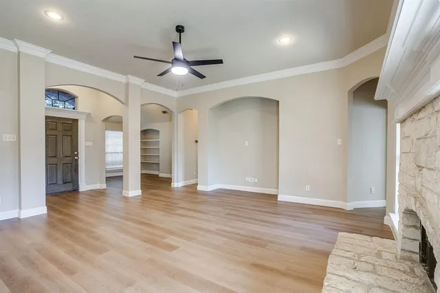 an empty room with wooden floor and a ceiling fan