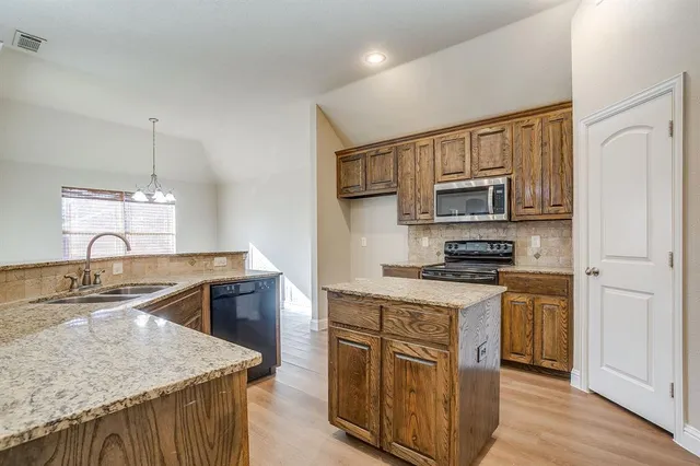 a kitchen with stainless steel appliances granite countertop a sink stove microwave and refrigerator