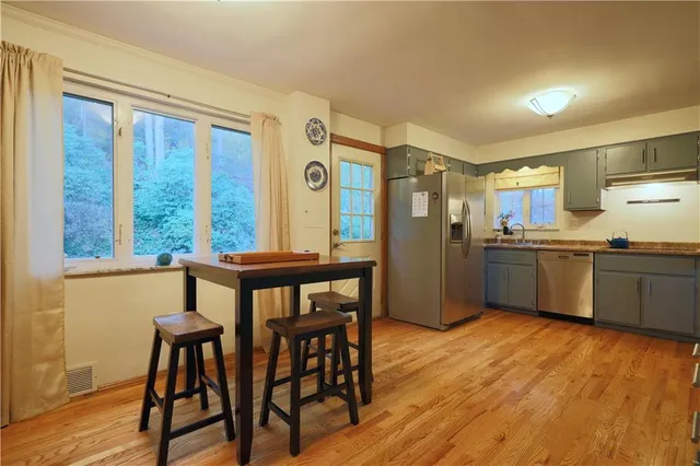 a kitchen with a table chairs refrigerator and wooden floor