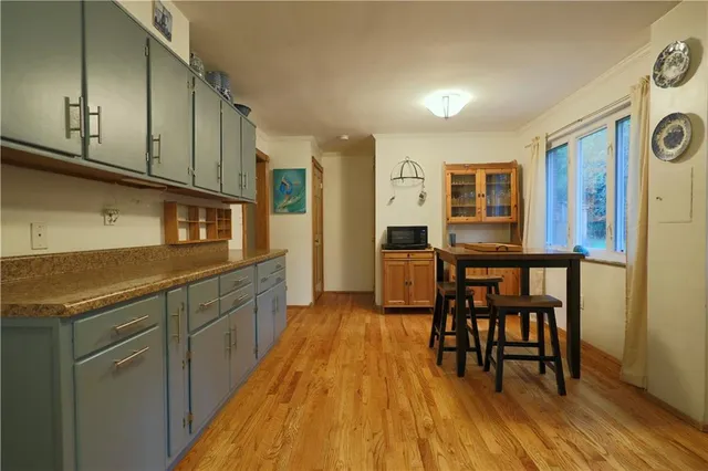 a kitchen with stainless steel appliances granite countertop a stove top oven a dining table and chairs with wooden floor