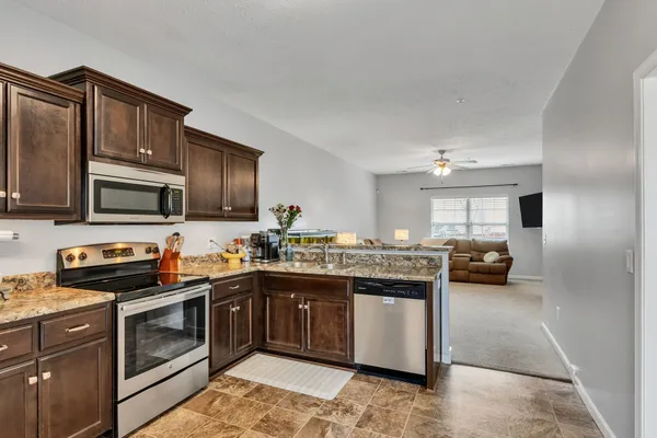 a kitchen with kitchen island granite countertop a sink and steel appliances