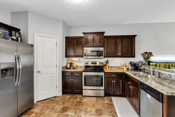 a kitchen with stainless steel appliances granite countertop a stove top oven a refrigerator and a sink