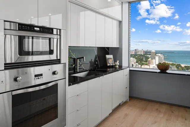 a living room with furniture large windows and a view of kitchen