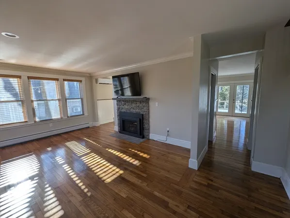 a view of empty room with wooden floor and fireplace