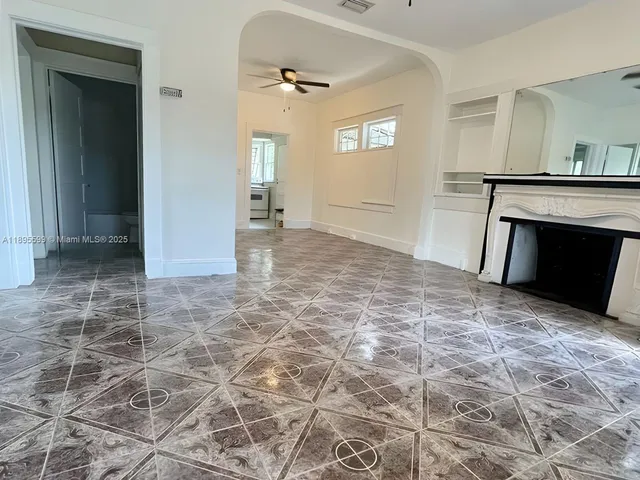 an empty room with windows and fireplace