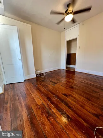 a view of empty room with wooden floor and fan