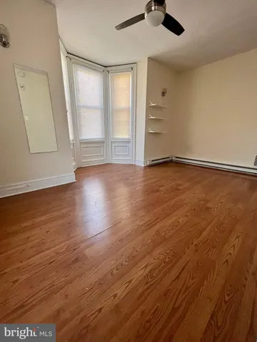 an empty room with wooden floor cabinet and windows