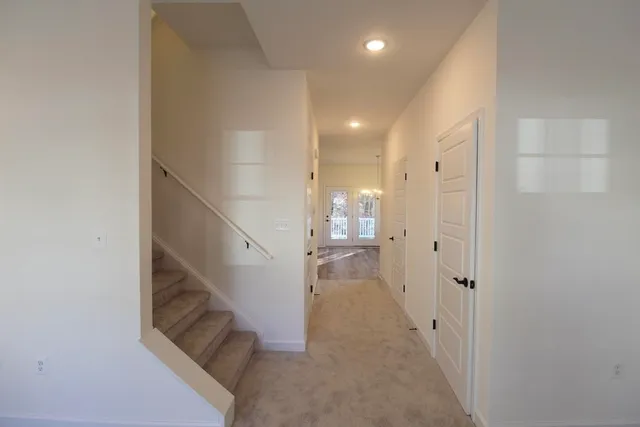 a view of a hallway with white walls and stairs