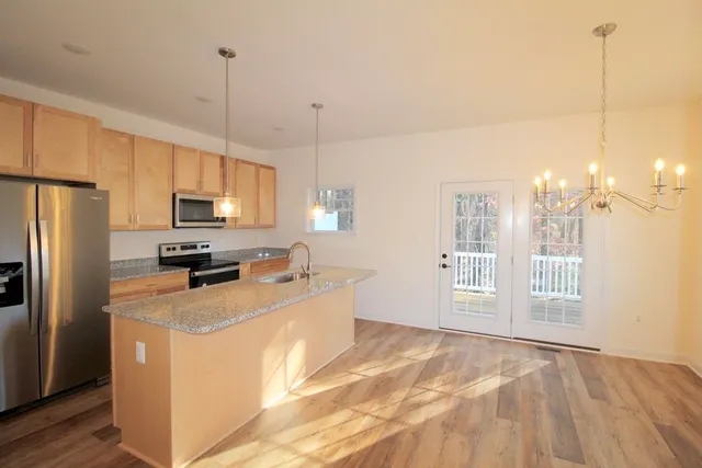 a kitchen with stainless steel appliances granite countertop a refrigerator a stove a sink and a center island