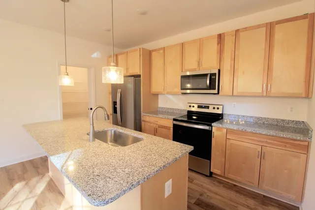 a kitchen with kitchen island granite countertop a stove top oven microwave and refrigerator