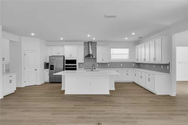 a large kitchen with stainless steel appliances a large counter top and kitchen island