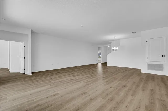 a view of kitchen and empty room with wooden floor