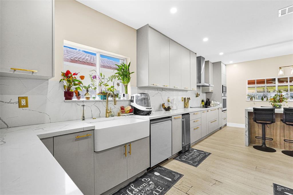 14402 Southwest 157th Path Miami, FL 33196 - Photo 7 of 80 a kitchen filled with white cabinets a sink dishwasher and a stove with wooden floor