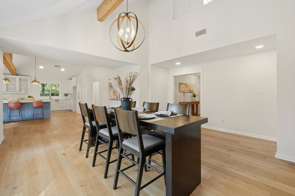 126 Pine View Loop Bastrop, TX 78602 - Photo 5 of 29 Spacious formal dining area with vaulted ceilings, striking faux beams, and an elegant chandelier, seamlessly open to the kitchen. Ideal for entertaining and hosting gatherings of any size.