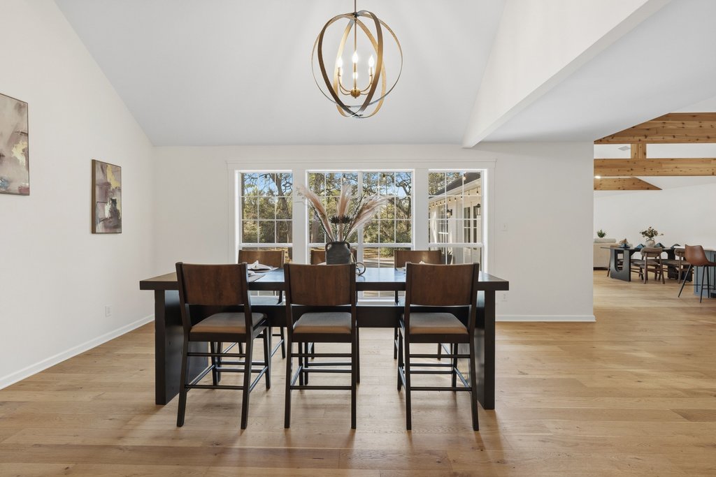 126 Pine View Loop Bastrop, TX 78602 - Photo 6 of 29 Spacious formal dining area with vaulted ceilings, striking faux beams, and an elegant chandelier, seamlessly open to the kitchen. ideal for entertaining and hosting gatherings of any size.