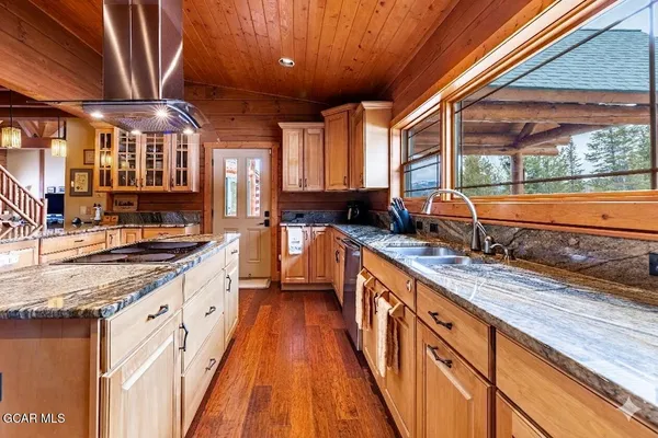a dining room with wooden floor a chandelier a glass table and chairs