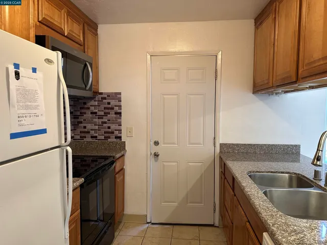 a kitchen with granite countertop a sink stove and refrigerator