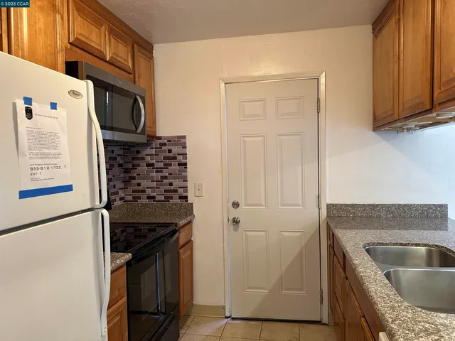 a kitchen with granite countertop a refrigerator and a sink