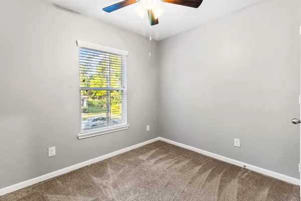 an empty room with a window and a fan