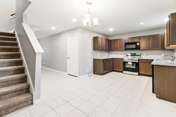 a large white kitchen with stainless steel appliances kitchen island granite countertop a refrigerator and a stove top oven with wooden floor