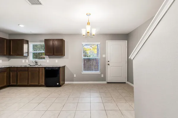 a kitchen with granite countertop a stove a microwave a sink a refrigerator and grey cabinets