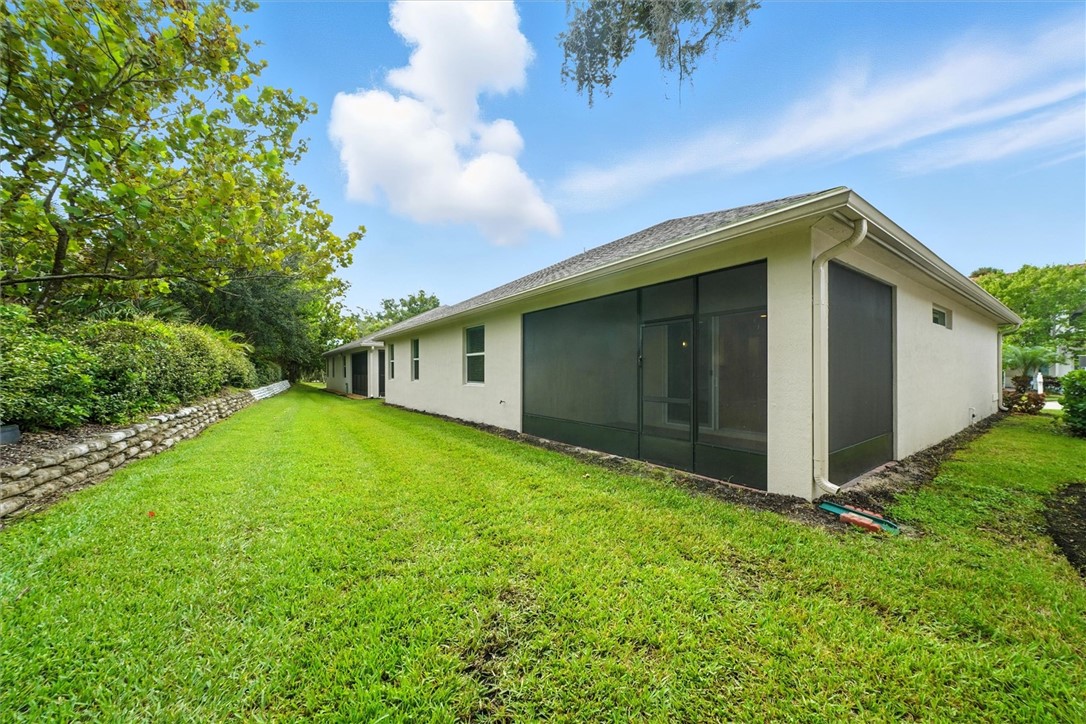 6096 Bella Rosa Lane Vero Beach, FL 32966 - Photo 23 of 33 a backyard of a house with plants and large tree