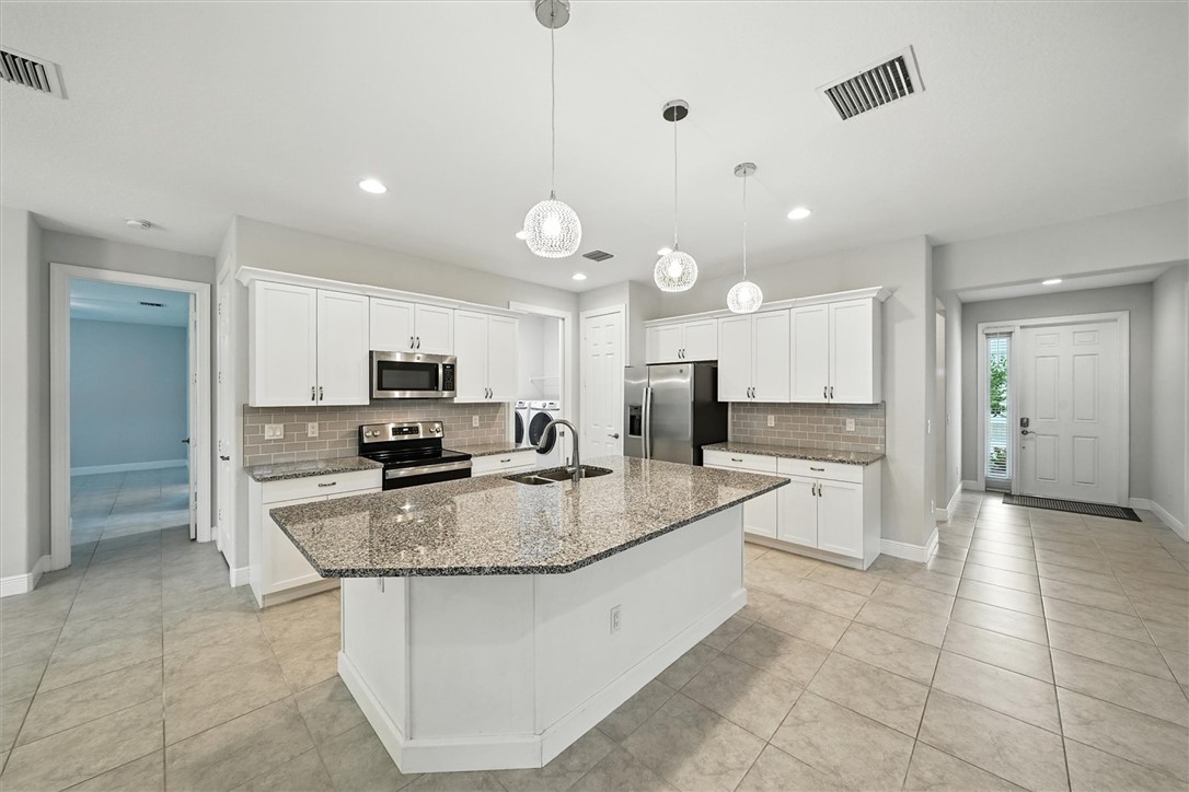 6096 Bella Rosa Lane Vero Beach, FL 32966 - Photo 4 of 33 a large kitchen with kitchen island a counter top appliances and cabinets