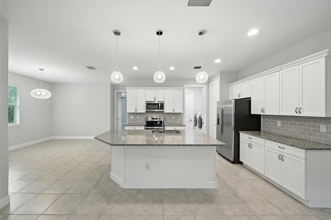 6096 Bella Rosa Lane Vero Beach, FL 32966 - Photo 6 of 33 a large kitchen with a large counter top stainless steel appliances and cabinets