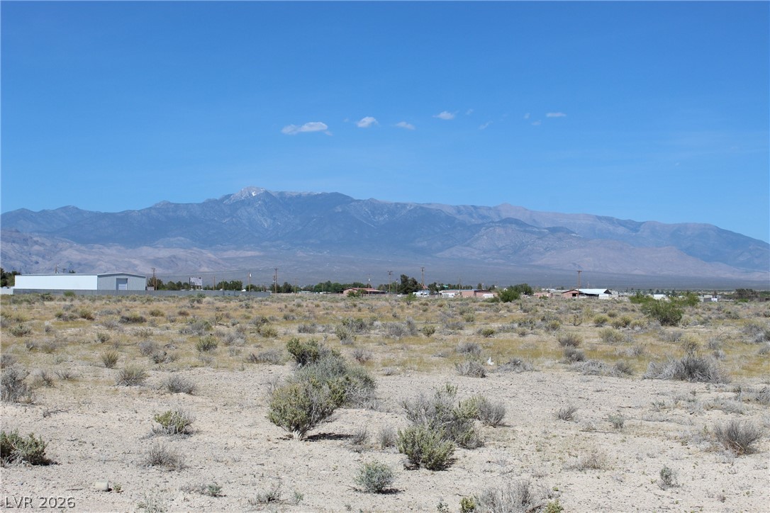 10091 Robert Road Pahrump, NV 89048 - Photo 2 of 7 Expansive desert terrain under a clear sky, offering picturesque mountain views.