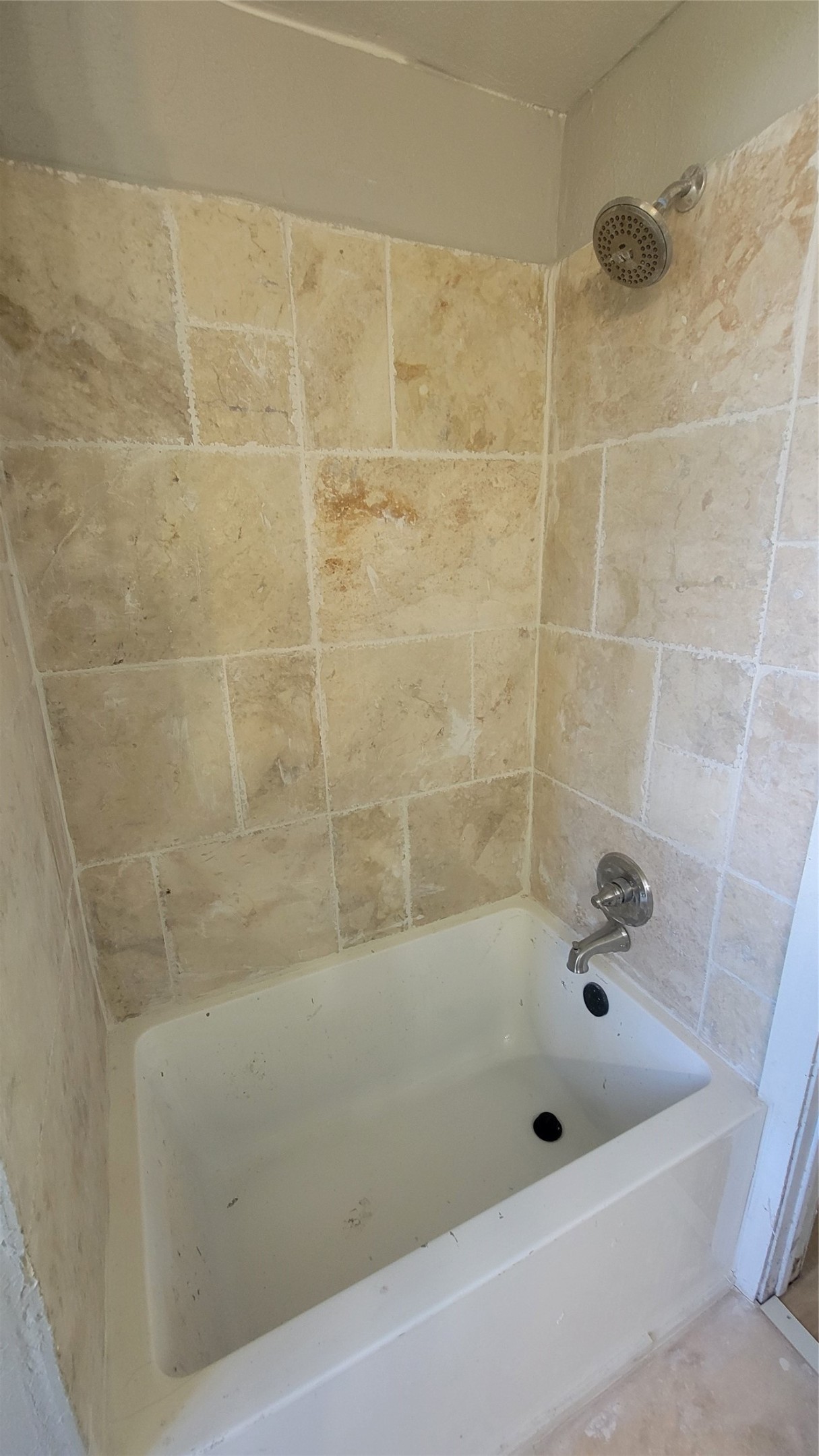 12018 Sandpiper Road Angleton, TX 77515 - Photo 16 of 48 This photo shows a bathroom with a tub and shower combination. The walls are tiled in a neutral stone pattern, and the fixtures are silver-toned.