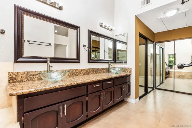 a bathroom with a granite countertop sink and a large mirror