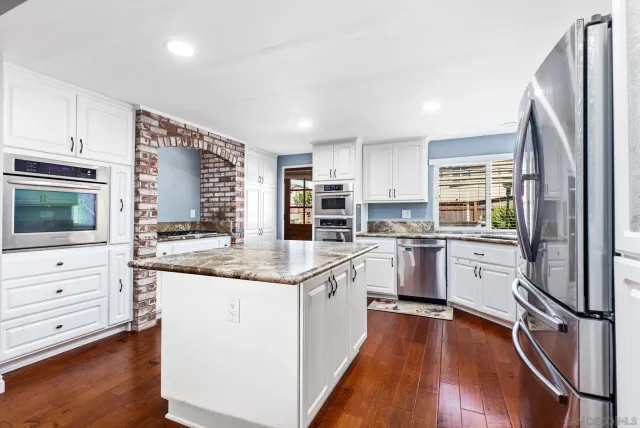 a kitchen with granite countertop white cabinets and white appliances