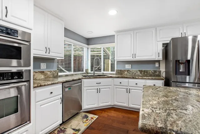 a kitchen with stainless steel appliances granite countertop a stove a sink and a refrigerator