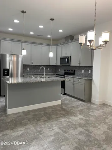 a kitchen with stainless steel appliances granite countertop a sink a stove a refrigerator and cabinets