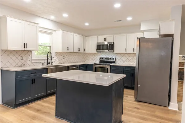a kitchen with stainless steel appliances granite countertop a sink stove a refrigerator and white cabinets