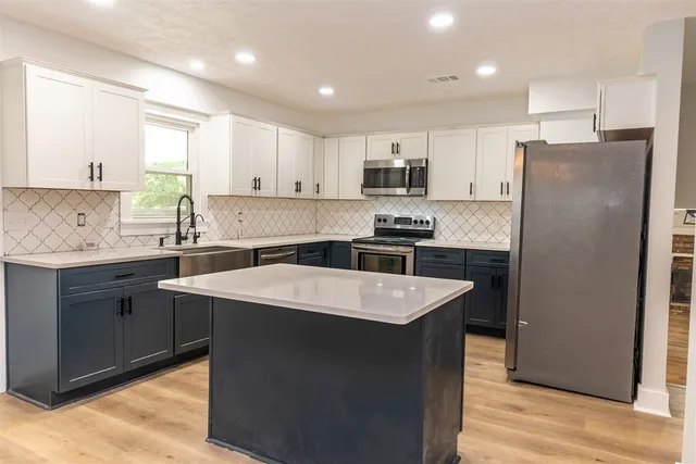 a kitchen with stainless steel appliances granite countertop a sink stove a refrigerator and white cabinets