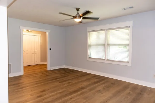 a view of an empty room with wooden floor and a window