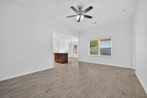 a view of an empty room with a window and wooden floor