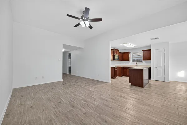 a view of an empty room with wooden floor fridge and a window