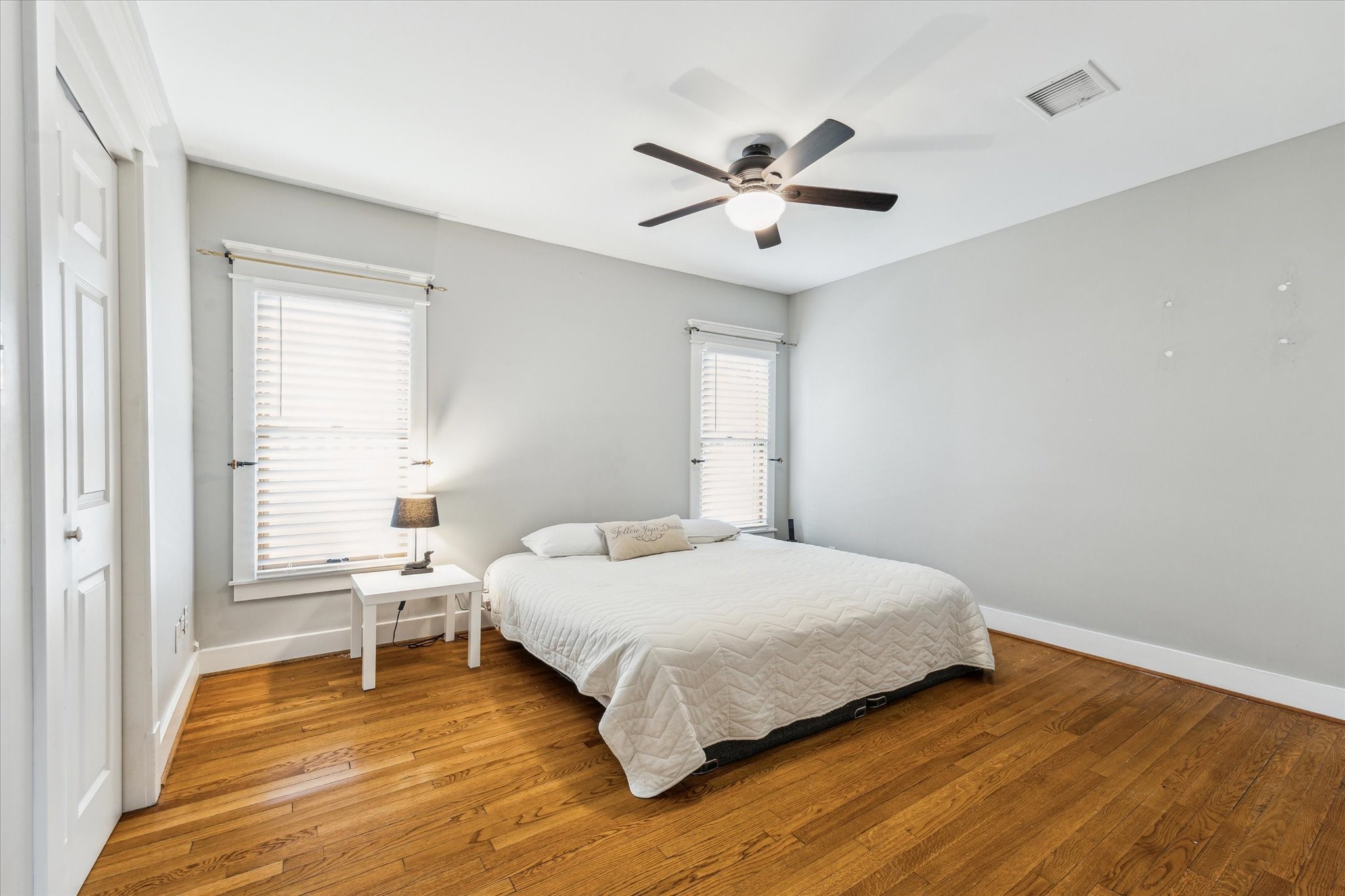 1321 West 21st Street Houston, TX 77008 - Photo 17 of 31 The primary bedroom is generously sized and thoughtfully laid out, offering plenty of room for a king-size bed, nightstands, and additional furniture such as a dresser or seating area. Two windows allow for excellent natural light while maintaining privacy, making the space feel open and inviting. The room’s layout supports flexible furniture placement, ideal for creating a relaxing retreat with both sleeping and lounging area.