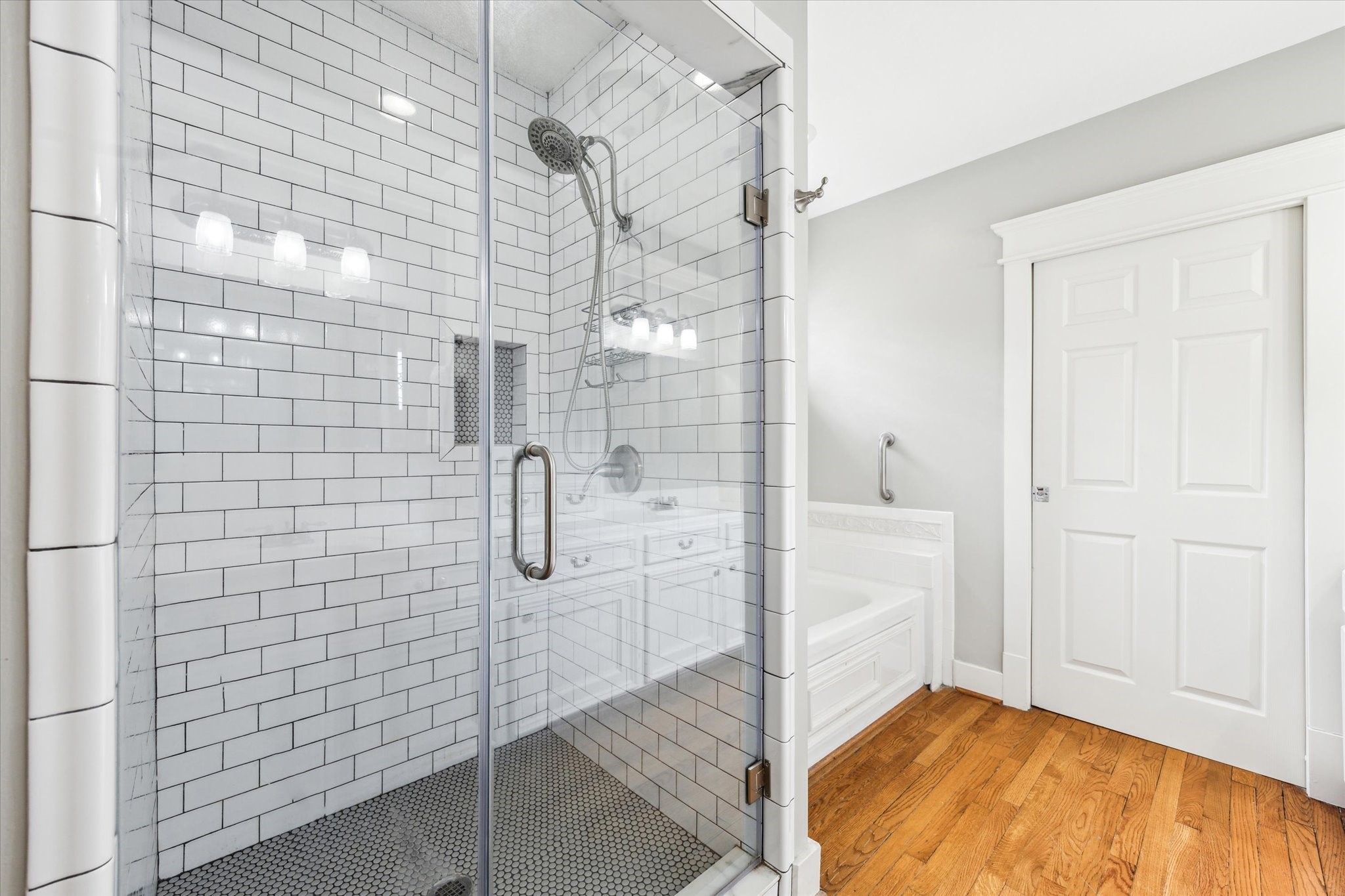 1321 West 21st Street Houston, TX 77008 - Photo 18 of 31 a walk-in glass shower with classic subway tile and upgraded fixtures. Easy access to the soaking tub, creating a bright and functional retreat.