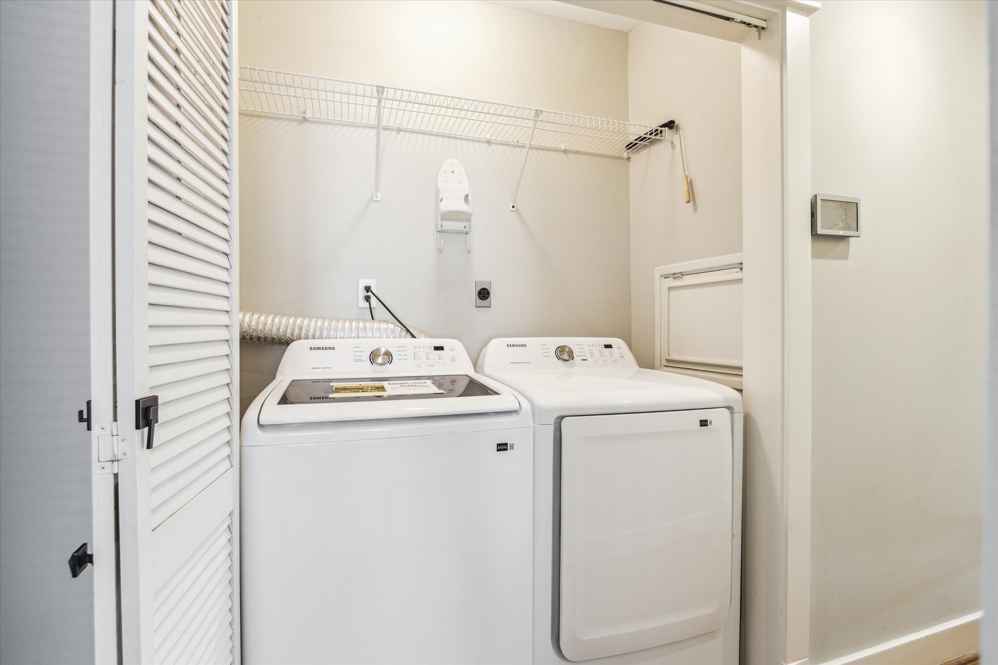 1321 West 21st Street Houston, TX 77008 - Photo 21 of 31 This dedicated laundry area features a full-size washer and dryer with convenient overhead shelving for storage and organization. The layout allows for easy access and efficient use of space, making everyday laundry tasks simple and functional. A built-in wall access panel and clean, neutral finishes enhance practicality while keeping the area tidy and unobtrusive within the home.