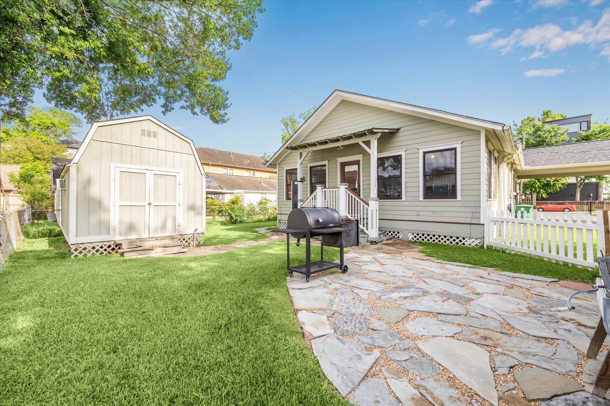 1321 West 21st Street Houston, TX 77008 - Photo 24 of 31 This backyard offers versatile outdoor living space ideal for entertaining, relaxing, or everyday enjoyment. The stone patio provides a dedicated area for grilling and outdoor dining, while the open lawn allows for play, pets, or garden use.