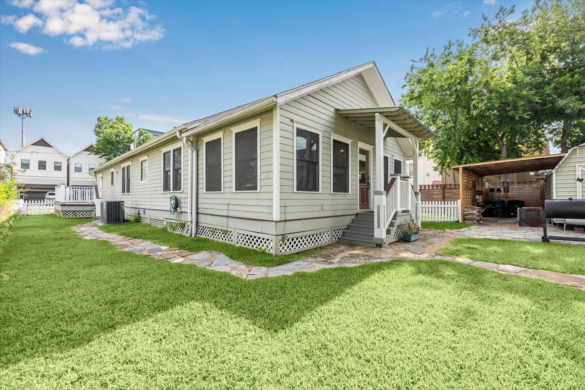 1321 West 21st Street Houston, TX 77008 - Photo 25 of 31 This exterior view highlights the home’s well-maintained siding, covered back entry, and stone walkway that wraps around the property.