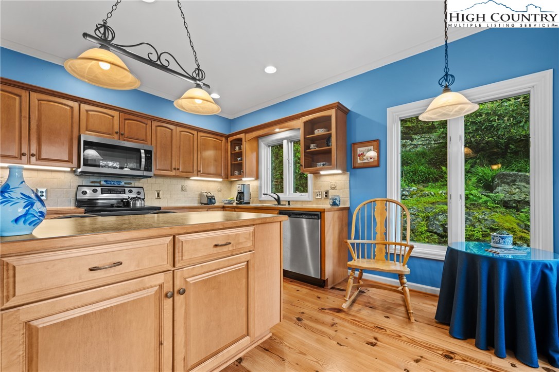 349 Belmont Drive Boone, NC 28607 - Photo 19 of 49 a kitchen with stainless steel appliances granite countertop a stove top oven a sink dishwasher a dining table and chairs with wooden floor