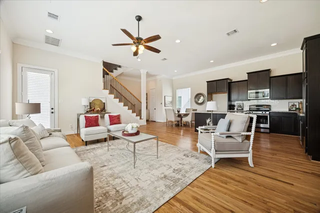a living room with furniture kitchen view and a wooden floor