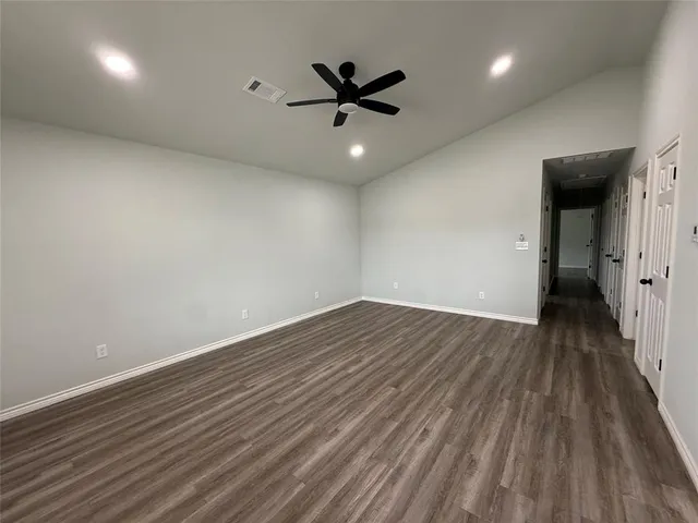 an empty room with wooden floor and a ceiling fan